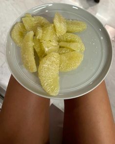 a person holding a white plate with orange slices on it and their legs in the air