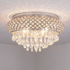 a crystal chandelier hanging from the ceiling in a room with white walls and flooring