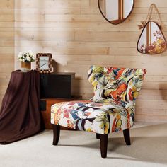 a colorful chair sitting in front of a wooden wall with mirrors on the wall behind it