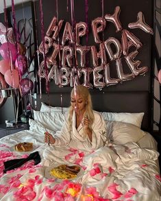 a woman laying in bed surrounded by balloons and confetti