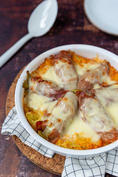 a casserole dish with meat and cheese in it on a wooden cutting board