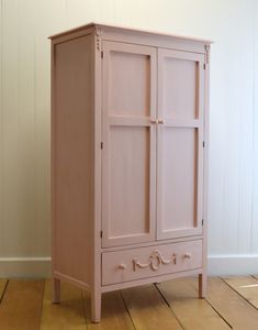 a pink armoire sitting on top of a wooden floor next to a white wall