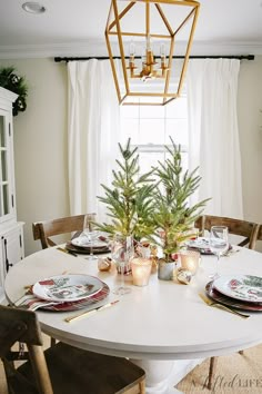 a dining room table with place settings and christmas decorations on the table, in front of a window