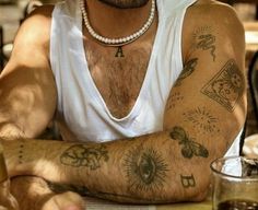 a man sitting at a table with tattoos on his arm