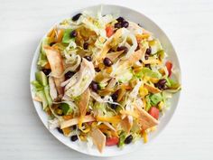 a white plate topped with a salad covered in lettuce, black beans and cheese