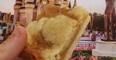 someone holding up a piece of food in front of a castle