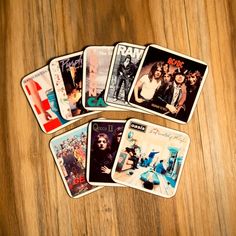 five coasters with the backs of famous rock bands on them, sitting on a wooden surface