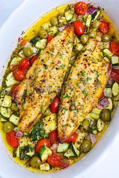 two fish fillets in a white bowl with tomatoes, zucchini and other vegetables