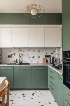 a kitchen with green cabinets and white counter tops is pictured in this image, there is a small dining table next to the sink