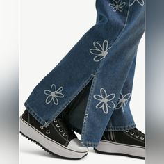 a pair of jeans with flower appliques on the bottom and side, are shown