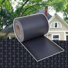 a roll of black vinyl sitting on top of a brick wall next to a house