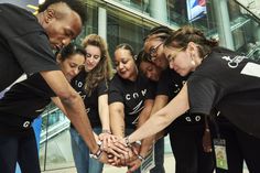 a group of people standing around each other in front of a glass building holding hands