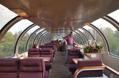 a man standing on the inside of a train car filled with lots of purple seats