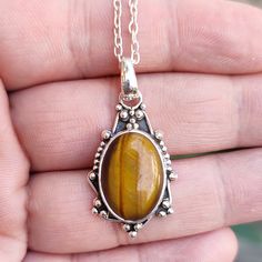 Description: Dive into the enchanting world of boho elegance with our Mystic Tiger's Eye Pendant. Inspired by the mystical allure of the tiger's eye stone, this handcrafted piece is meticulously crafted from 925 sterling silver, showcasing a beautiful, natural oval tiger's eye gemstone. Each pendant is a unique creation, making it the perfect birthstone gift for her. Story Behind the Creation: Inspired by the enchanting tales of ancient warriors and their protective amulets, our Mystic Tiger's Eye Pendant channels the power and beauty of the tiger's eye gemstone. This stone, believed to bring courage and strength, has been cherished through the ages for its captivating shimmer and mystical properties. Crafting Process: Every pendant is carefully handcrafted by skilled artisans, ensuring th Unique Handcrafted Jewelry, Boho Mode, Tigers Eye Gemstone, Birthstone, Tiger Eye Stone, Birthstone Gifts, Wedding Jewellery Necklace, Nature Jewelry, Jewelry Lover