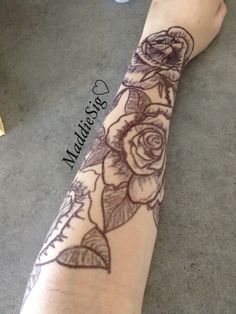 a person with a tattoo on their arm that has roses and leaves tattooed on it