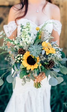 a bride holding a bouquet of sunflowers and greenery