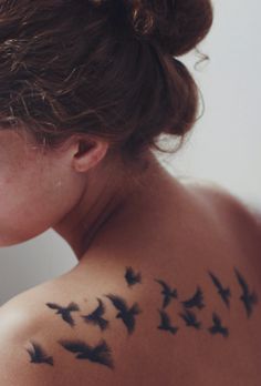 a woman with birds on her back tattoo