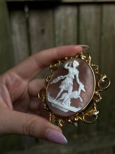 Romantic and whimsical, this rare 19th century brooch is a museum-quality adornment! Crafted circa 1850, this brooch is set in 12 carat gold and features a stunning Baroque frame. Also beautiful is the soft, rosey peach-hued cameo shell, upon which we see the delicate visage of the Greek Goddess Diana, and the Theban hero Actaeon in the form of a stag. As the myth goes, Diana was bathing at a hidden spring when Actaeon stumbled upon her naked figure. Outraged at the invasion of privacy, the embarrassed Diana punished Actaeon by destroying his power of speech, and turning him into a shaggy-haired stag with large antlers. And indeed, in this cameo, we see the figure of Artemis standing defiantly upright, one hand reaching for her quiver of arrows, and the other placed sternly upon the top of Elegant Yellow Gold Baroque Brooches, Yellow Gold Baroque Brooch For Formal Occasions, Formal Yellow Gold Baroque Brooches, Victorian Gold Brooch With Intricate Design, Gold Victorian Brooch With Intricate Design, Victorian Gold Brooches With Intricate Design, Gold Victorian Brooches With Intricate Design, Victorian Brooches With Intricate Design, Antique Brooch With Intricate Pendant Design