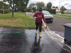 a woman is using a hose to clean the street