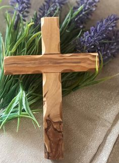 a wooden cross sitting next to lavender flowers