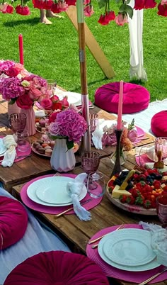 a table set up with plates and pink napkins for an outdoor party or brunch