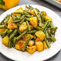 a white plate topped with green beans and potatoes