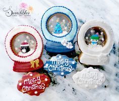 four decorated christmas cookies sitting on top of a marble counter with snowflakes in the background