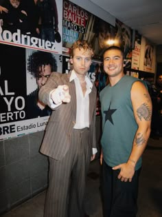 two men standing next to each other in front of posters