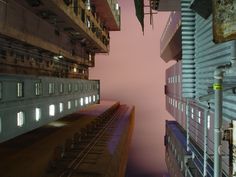 looking up at tall buildings in an urban setting with pink sky and clouds behind them