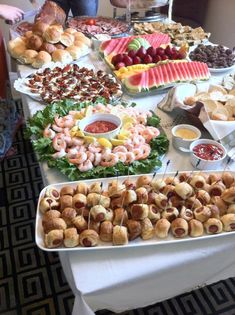 a table filled with lots of food on top of a white tablecloth covered table