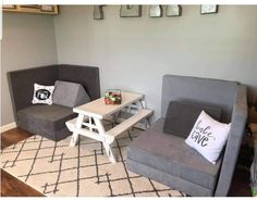 a living room with two gray couches and a white table in the middle of it