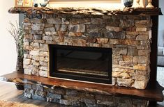 a stone fireplace in a living room next to a wall with pictures on top of it