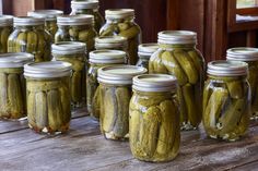 several jars filled with pickles sitting on top of a wooden table