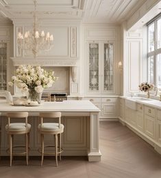 an elegant kitchen with white cabinets and marble counter tops, chandelier above the island