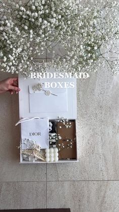 a white box filled with jewelry next to a wall covered in flowers and pearls on the floor