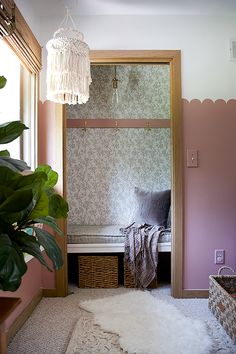 a room with a bench, rug and potted plant in the window sill