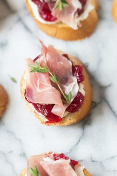 small appetizers with meat and cheese on them are arranged on a marble surface