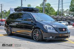 a black van with a surfboard on the roof is parked in a parking lot