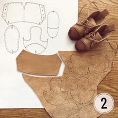 a pair of brown shoes sitting on top of a wooden table next to a piece of paper