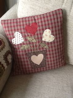 a plaid pillow with hearts on it sitting on a couch