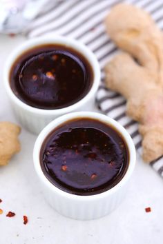 two small white bowls filled with sauce next to ginger cookies