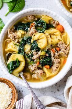 two bowls filled with pasta and spinach soup on top of a white countertop