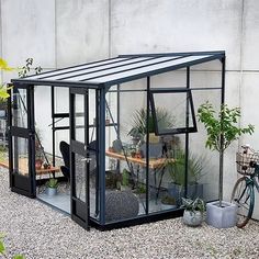 there is a small greenhouse with plants in the corner and a bicycle parked next to it