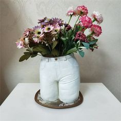 a vase filled with flowers sitting on top of a white table next to a wall