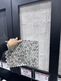 a person's hand is holding up a pile of toilet paper in a store