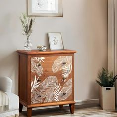 a wooden cabinet with leaves painted on the front and sides, in a living room