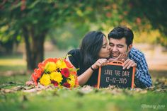 a man and woman laying on the ground kissing each other with flowers in front of them