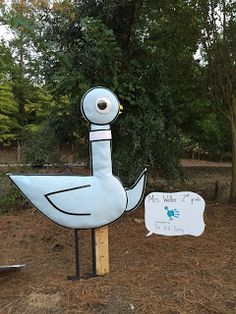 there is a large blue duck statue in the yard next to a sign that says it's water