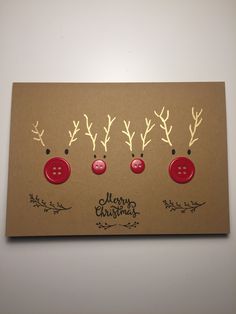 three red buttons with reindeer antlers on them are attached to a brown card that says merry christmas