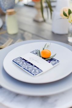 a white plate topped with an orange on top of a blue and white place setting